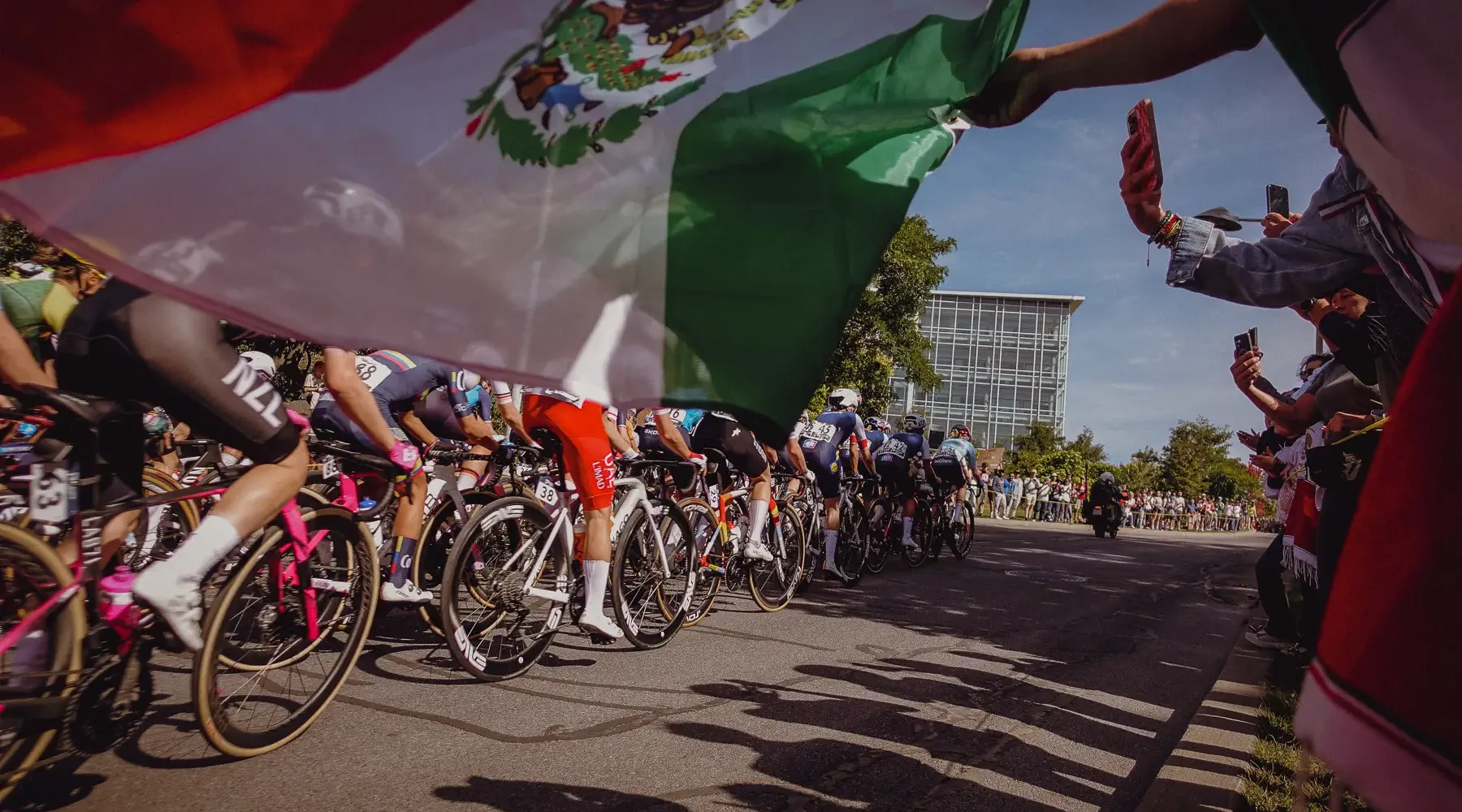 A huge Mexican flag sweeps above the peloton as riders pass through the Mount Royal crowds