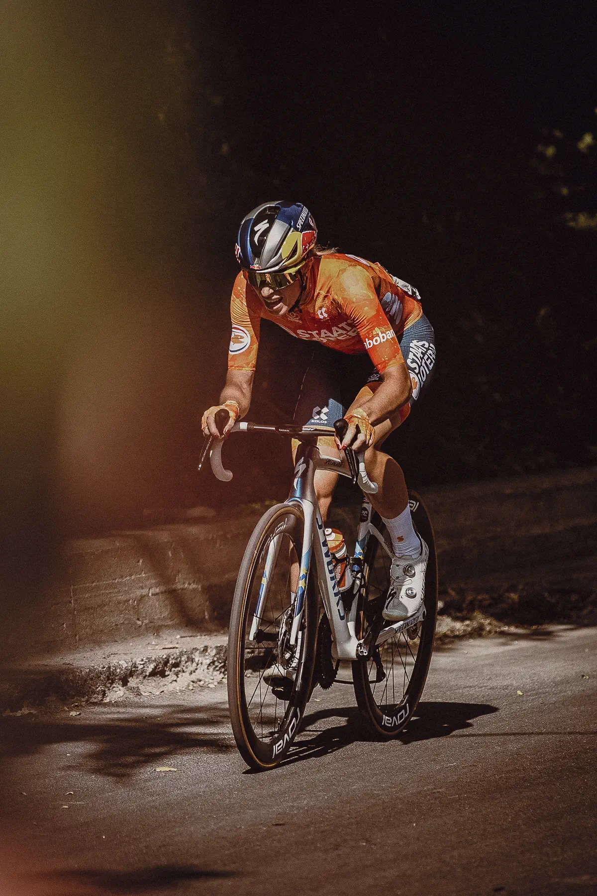 A lone Netherlands rider climbs through a dark, tree-lined section of Mount Royal