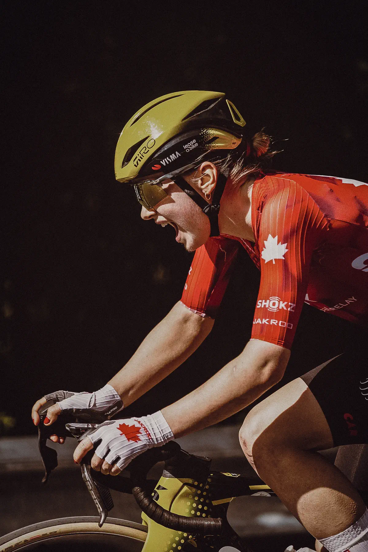 A rider in red national colors pushes through the effort beneath a bright yellow helmet on Mount Royal