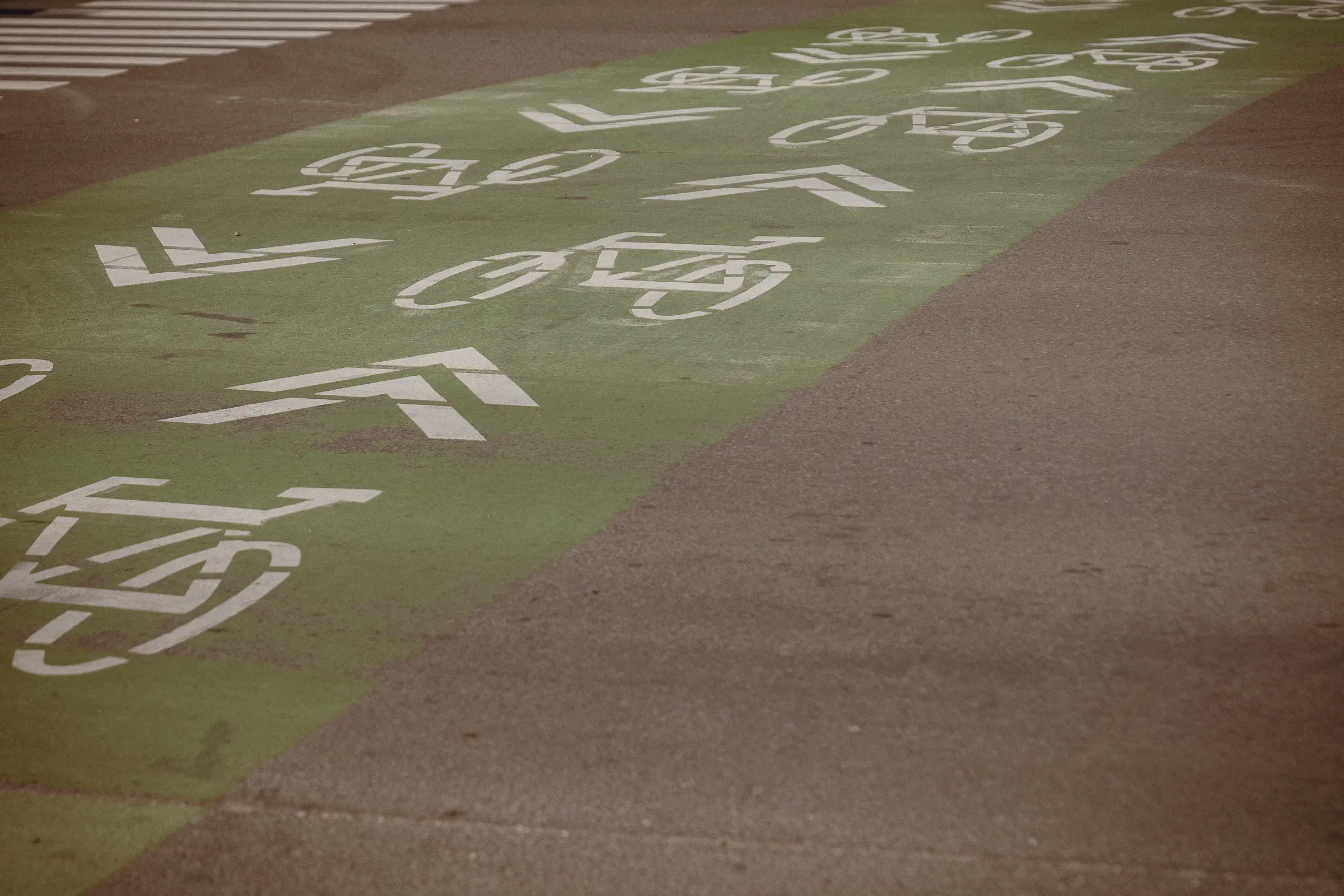 White bicycle symbols repeat across a green Montréal cycle lane