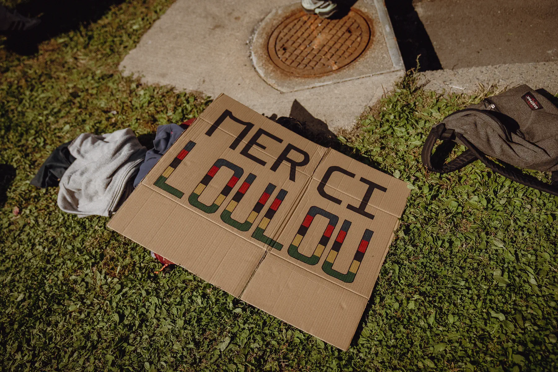 A handmade “MERCI” sign lies on the grass after the riders and crowds have moved on