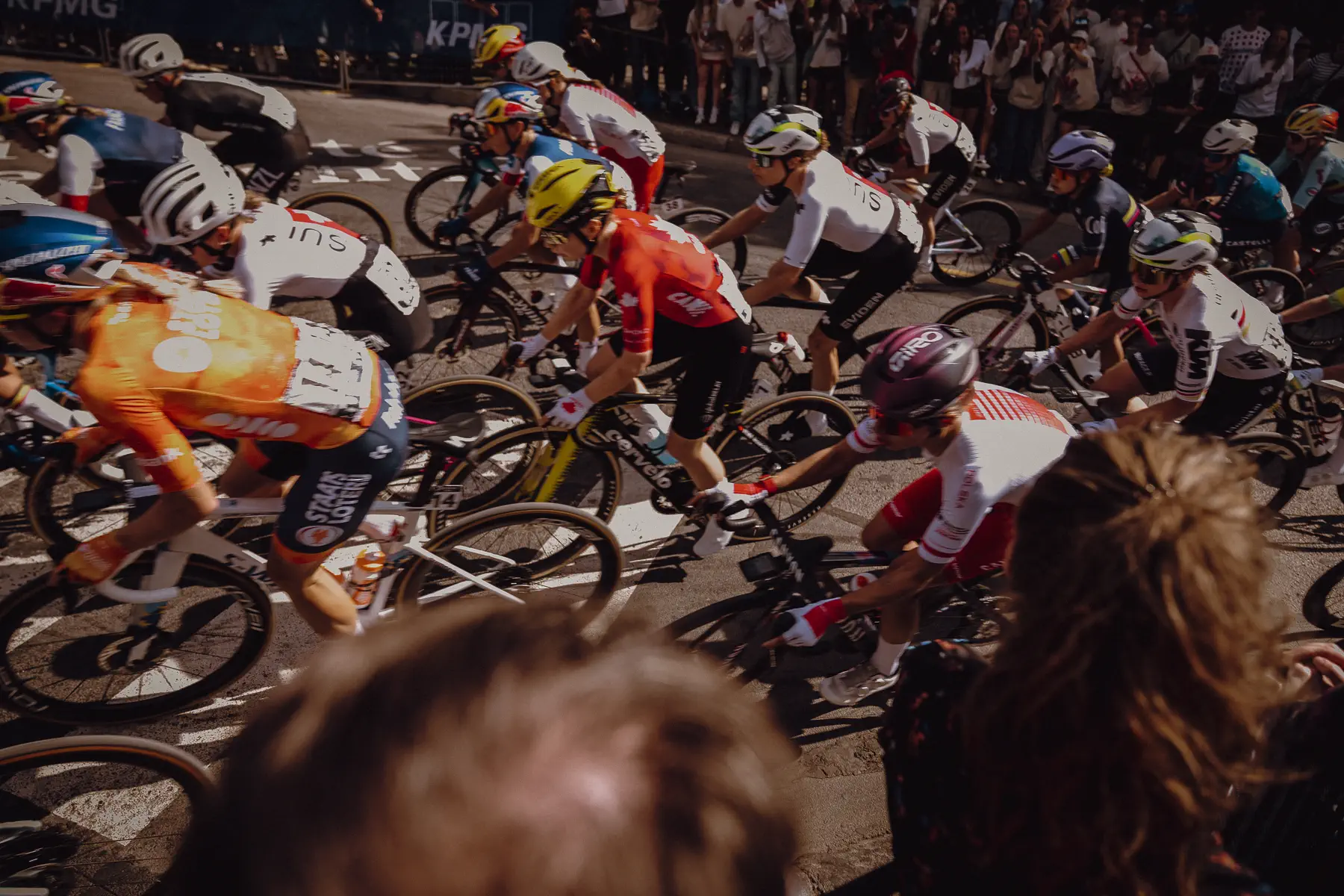 A tightly packed group of riders fills the frame from above during the women’s road race