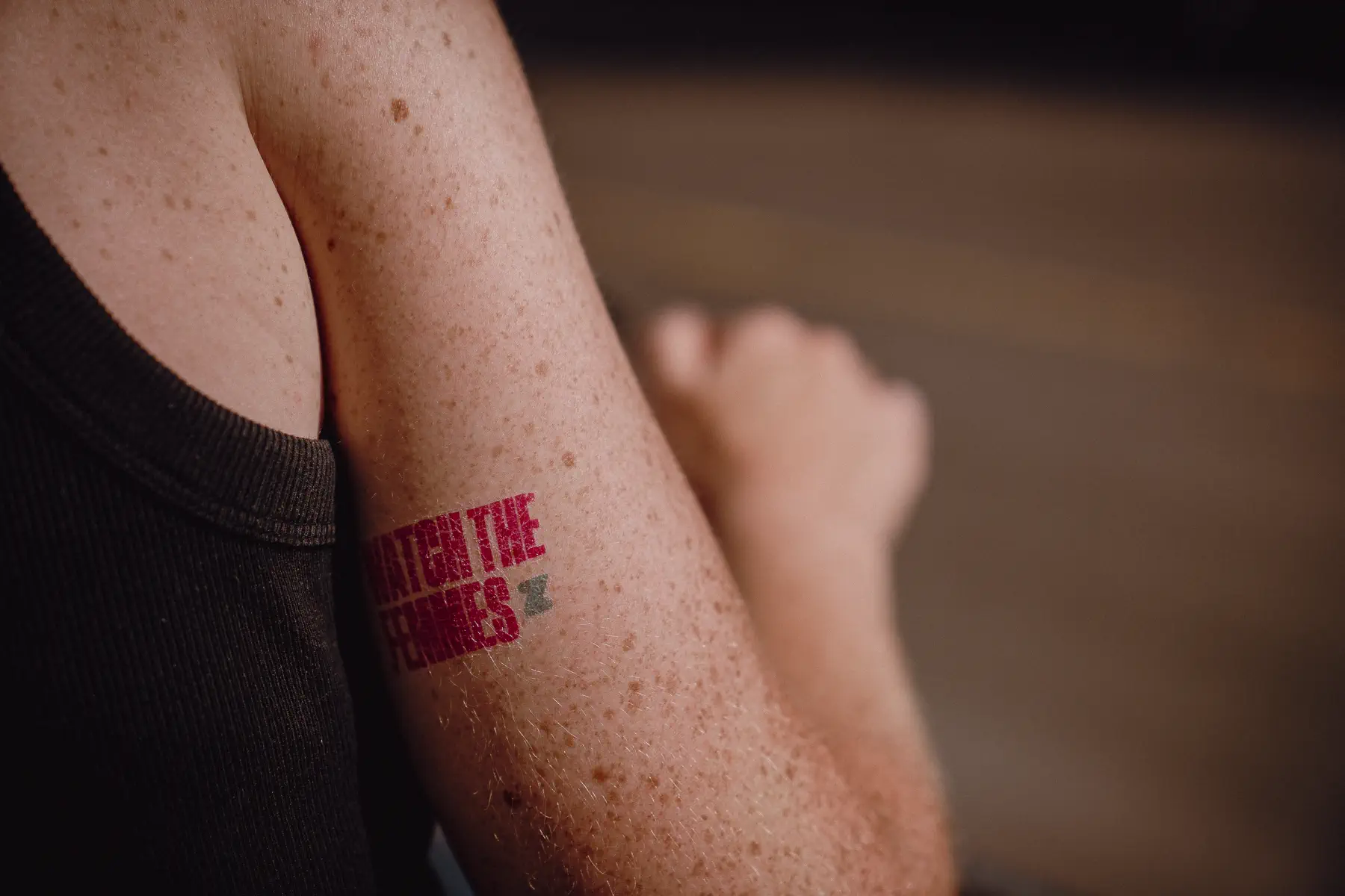 A small red cycling-themed race-week stamp sits on a spectator’s forearm