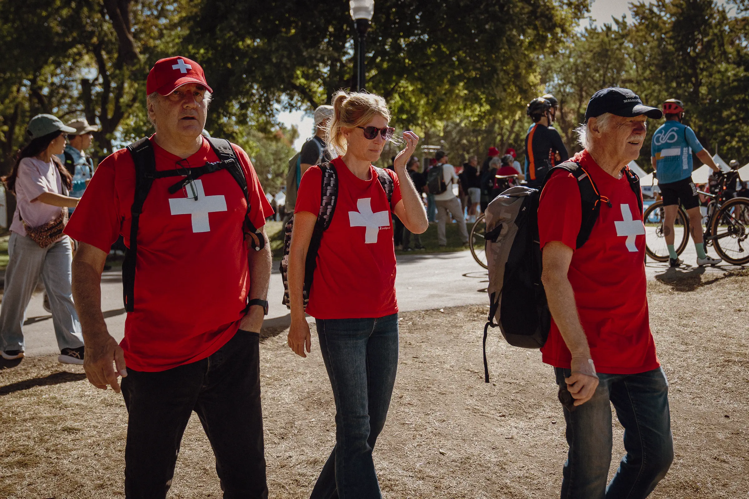 Three Swiss supporters walk together in red shirts beside the Montréal course after the race