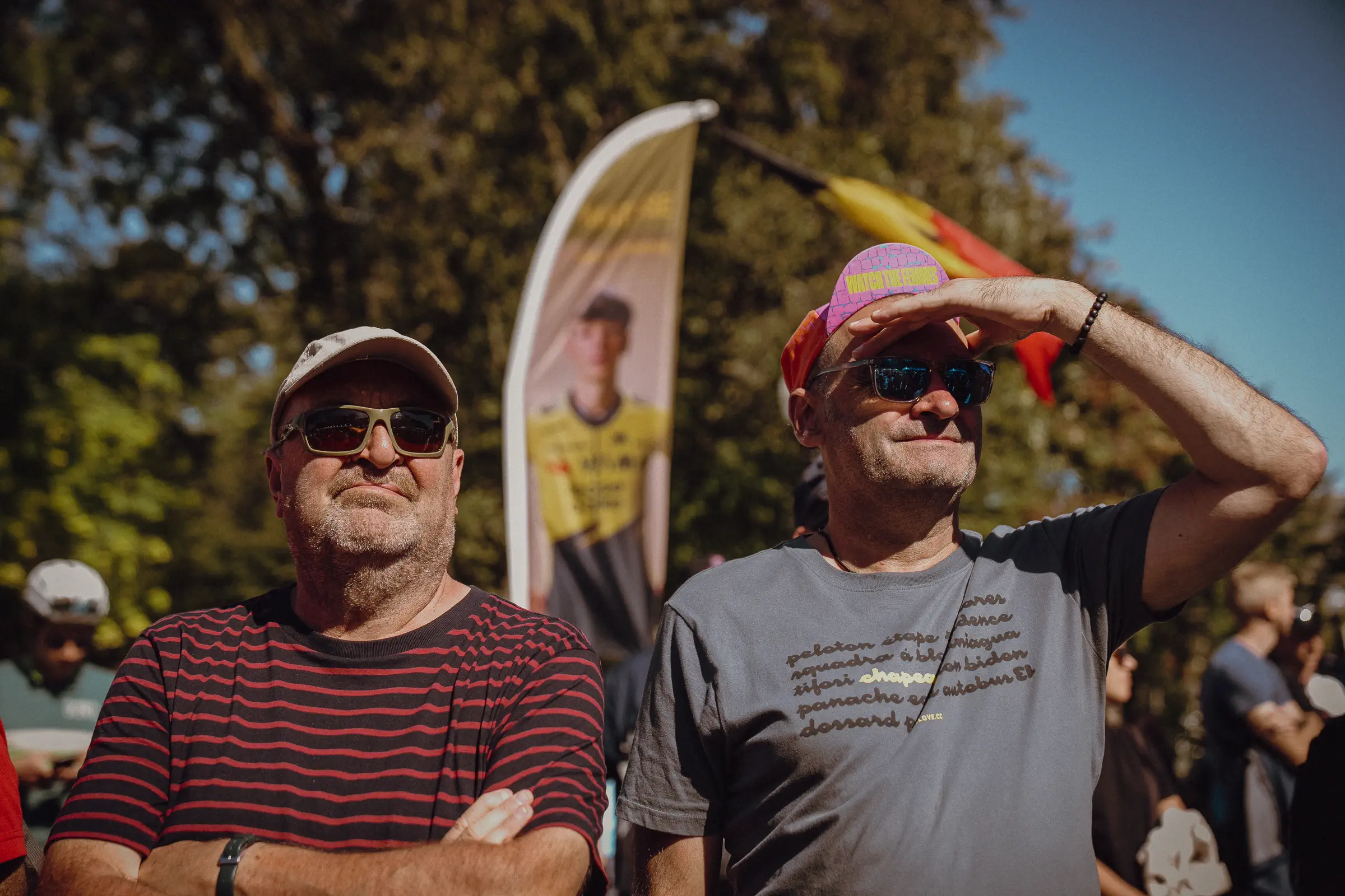 Two spectators look toward the course in warm late-day light as the final race-day hours pass