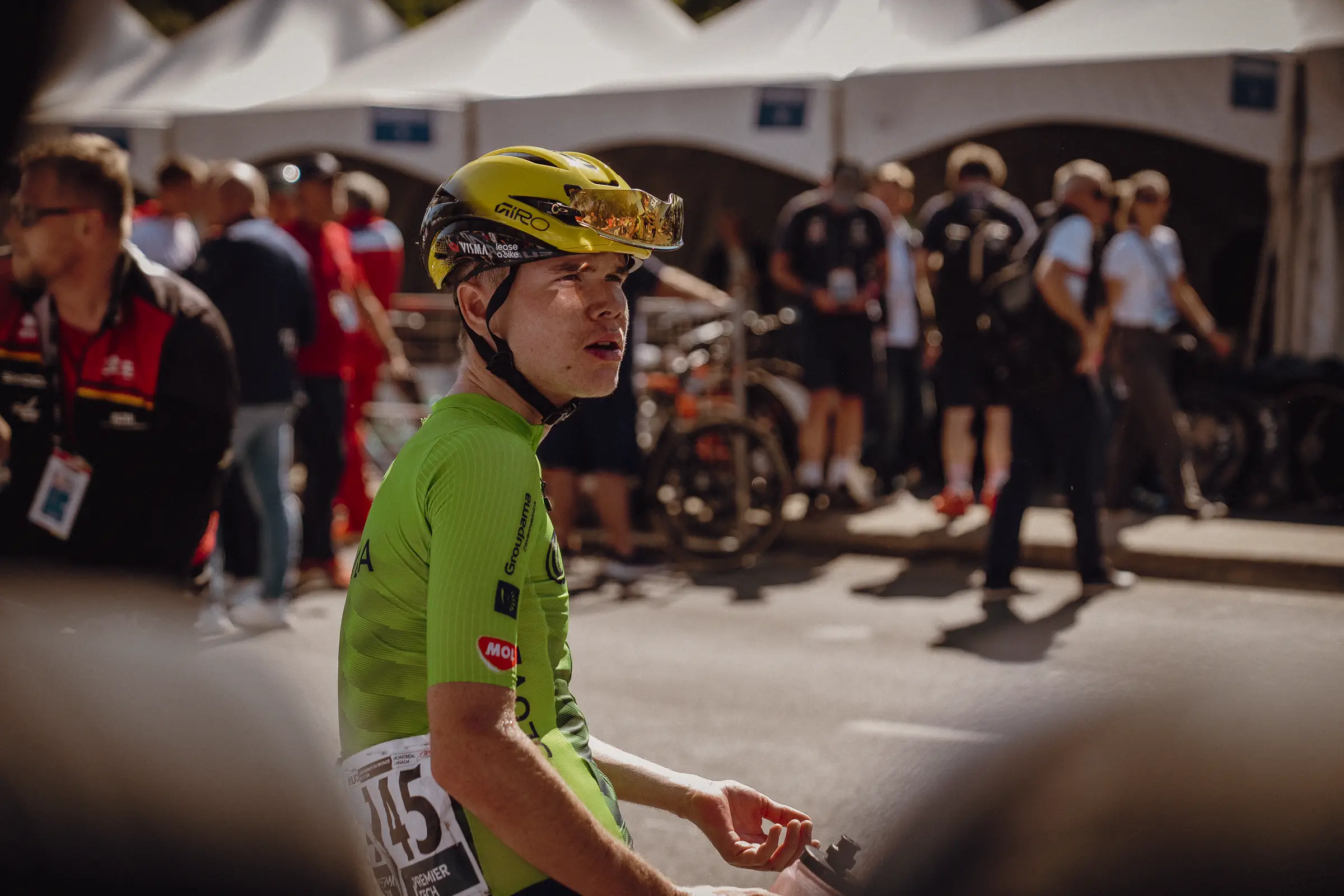 A rider in the team area catches his breath after the race with staff and bikes behind him