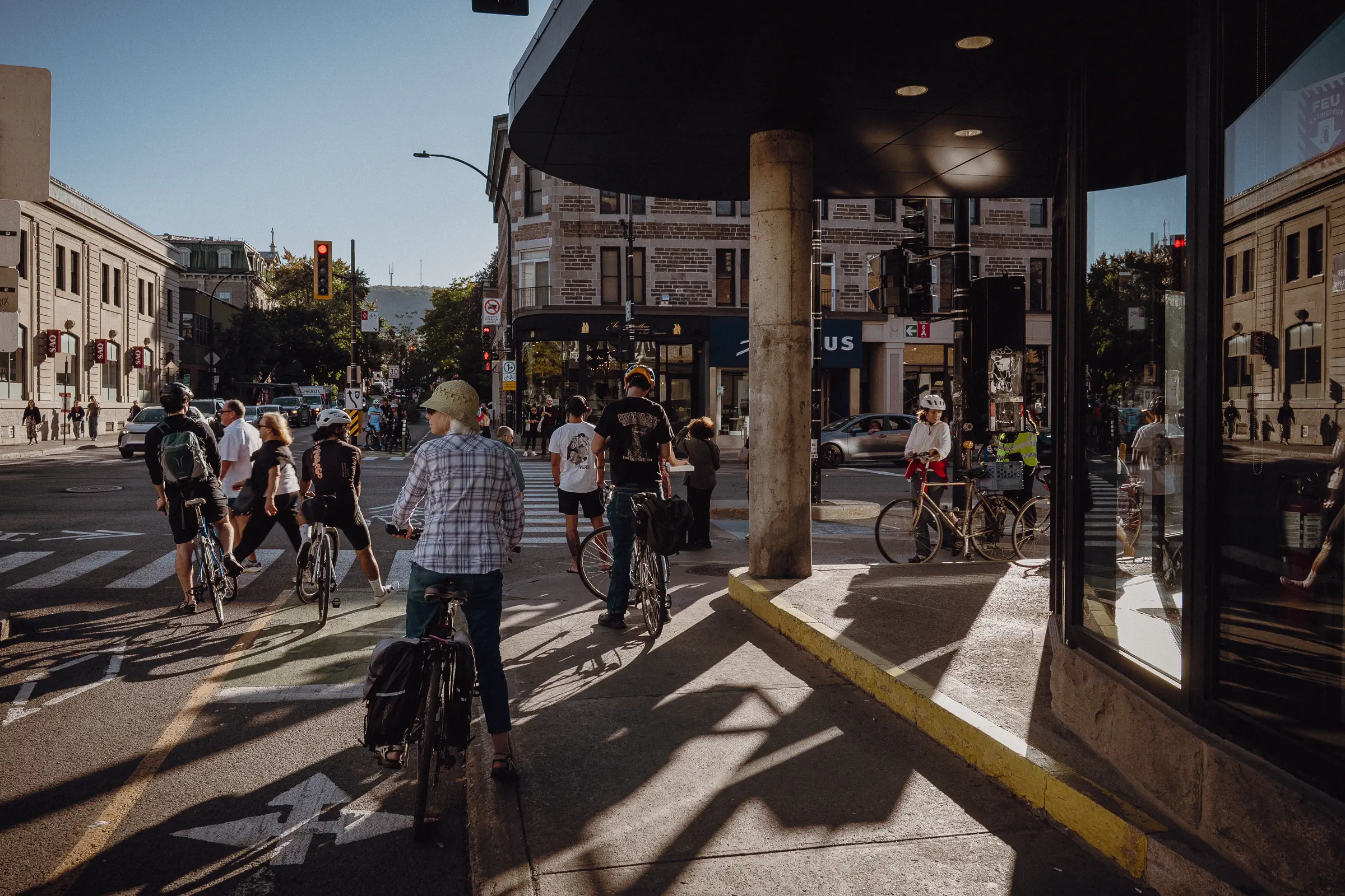 People move through a sunlit Montréal street during race week, with bicycles woven into the everyday city scene