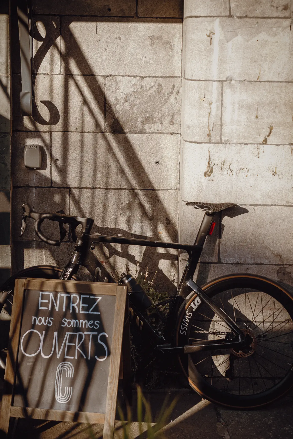 A bicycle rests in shadow against a Montréal wall between race-week movements