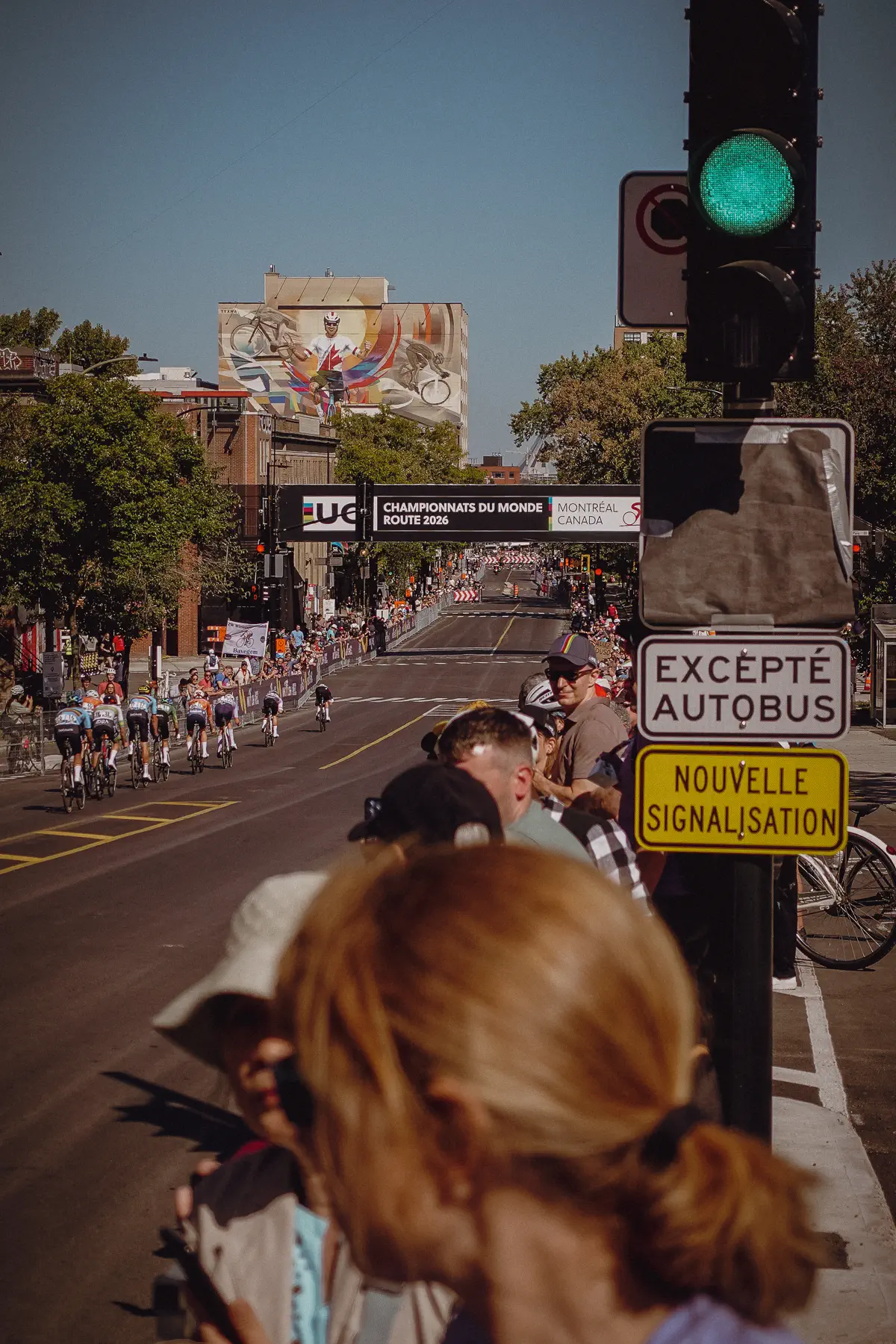 World Championship riders enter a crowded Montréal intersection beneath course signs and traffic lights