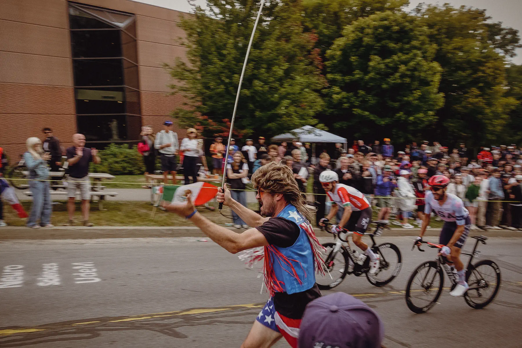 A roadside spectator reaches toward the riders as the race flashes past at arm’s length