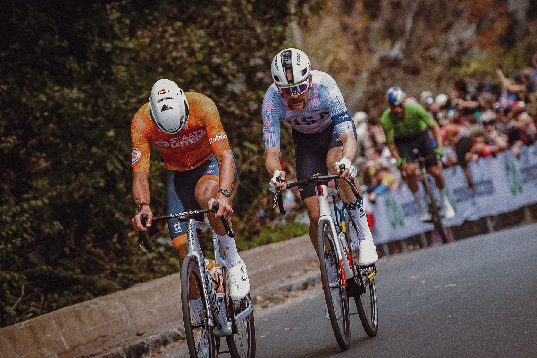 Two riders push clear of a strung-out group on the climb as fans line the road