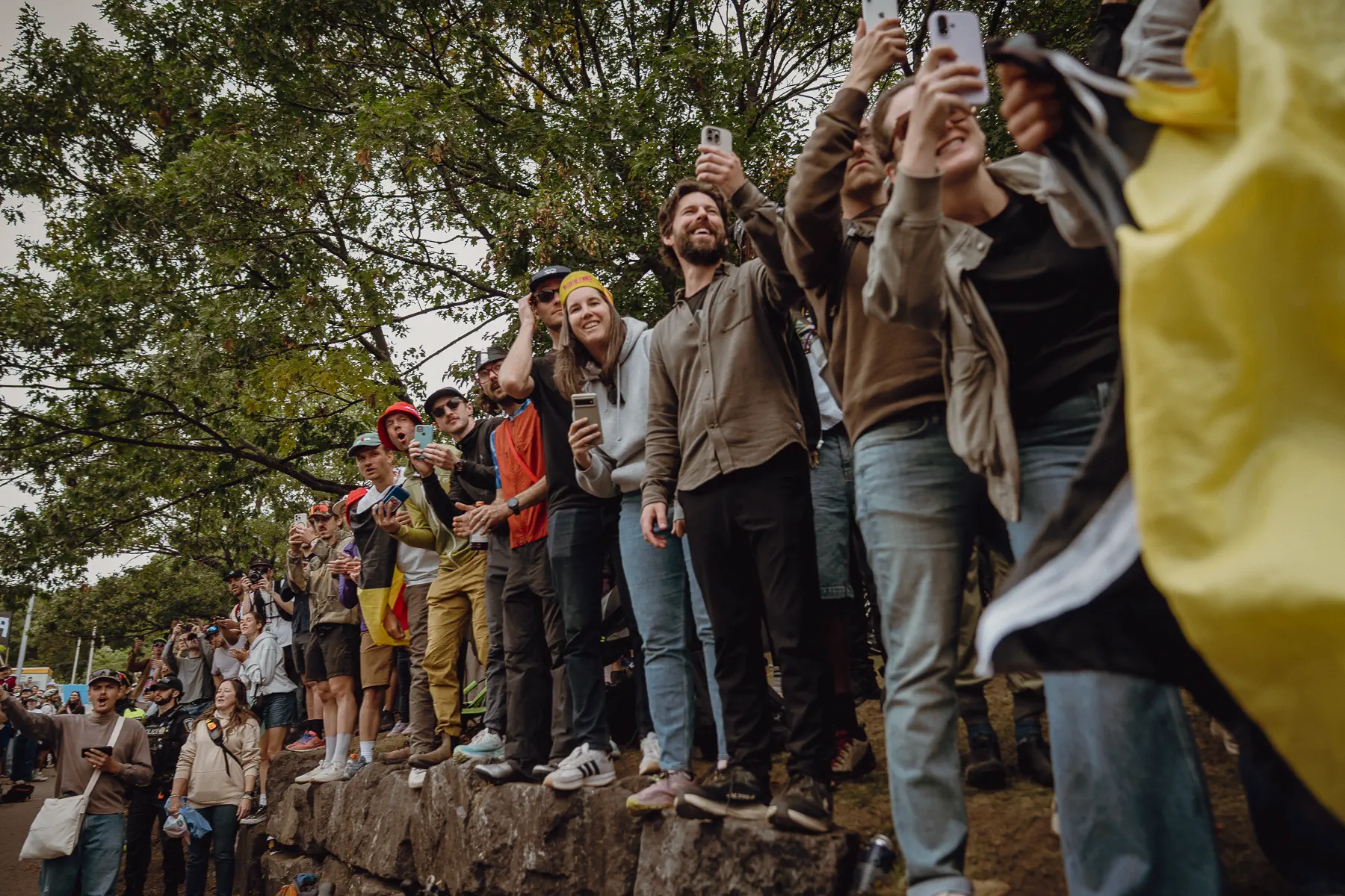 Fans lean from the rocks and roadside, reacting as the race passes below them
