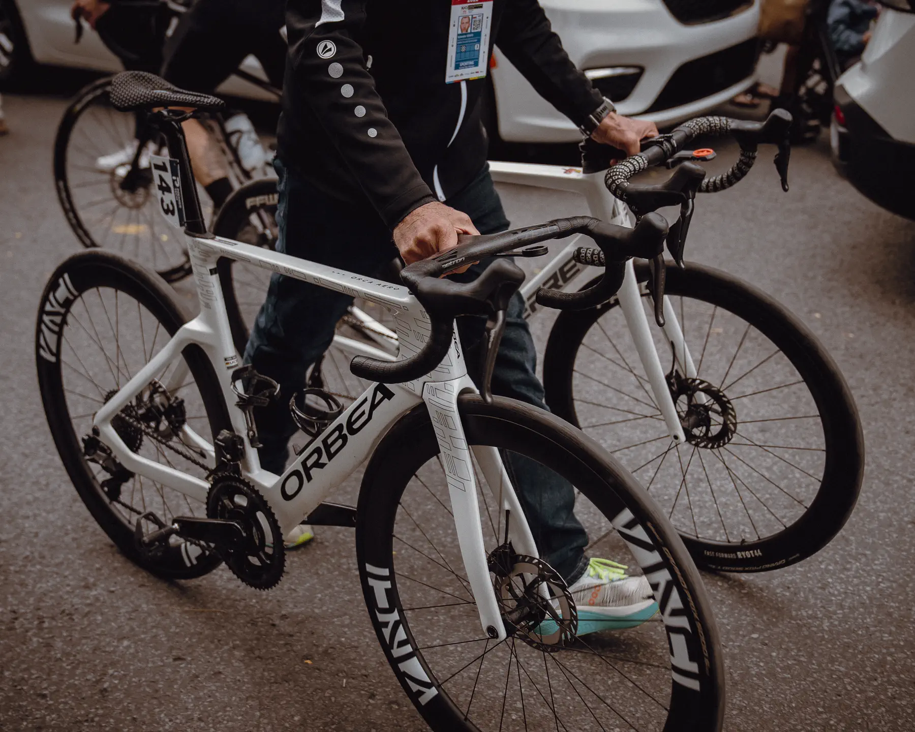Race bikes and team equipment cluster tightly beside support staff before the start